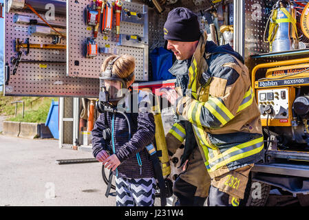 Hoby Brakne, Schweden - 22. April 2017: Dokumentation der öffentlichen Feuer LKW Präsentation. Feuerwehrmann helfende junge versuchen ein umluftunabhängiges appa Stockfoto