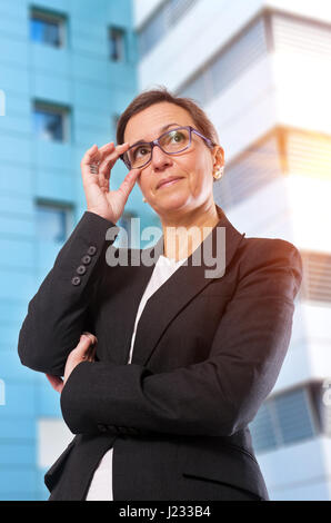 Brünette Business-Frau mit Brille posiert vor Bürogebäude Stockfoto