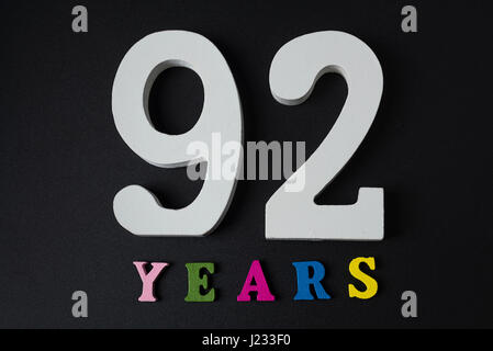 Buchstaben und Zahlen zweiundneunzig Jahren auf schwarzem Hintergrund isoliert. Stockfoto