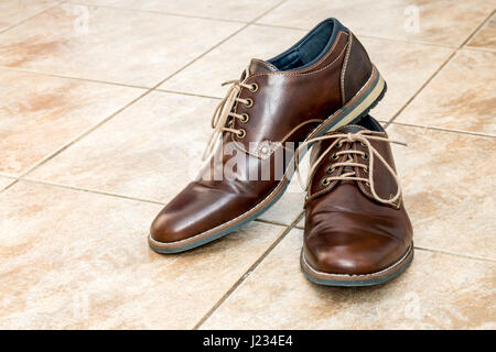 Paar der Mode braun Herrenschuhe mit Schnürsenkel auf einen leichten braunen Keramikfliesen Stockfoto