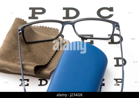 Schwarze Brillen, braun Mikrofaser Tuch und blau Schutzhülle mit weißem Auge Diagramm Nahaufnahme Reinigung lesen Stockfoto