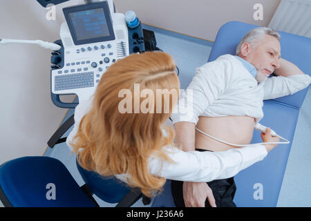 Qualifizierte junge Sanitäter eine Ultraschall-Untersuchung in der Sonographie Kabinett Stockfoto