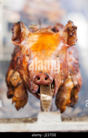 Traditionell Spanferkel auf einer sich drehenden Spieß mit Feuer und Rauch. Sehr leckeres Essen. Stockfoto