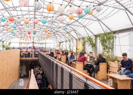 Menschen Essen und trinken in das Gewächshaus, ist eine große überdachte Folientunnel in Pop Brixton.Pop Brixton, Veranstaltungsort und die Heimat einer Gemeinschaft Stockfoto