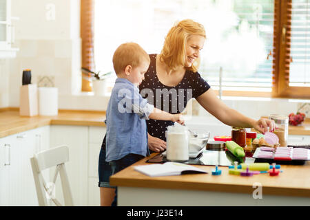 Kind hilft Mutter machen Cookies in modernen Küche Stockfoto