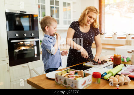 Kind hilft Mutter machen Cookies in modernen Küche Stockfoto