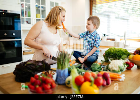 Schwangere Frau mit Sohn aus frischem Gemüse Zubereitung Stockfoto
