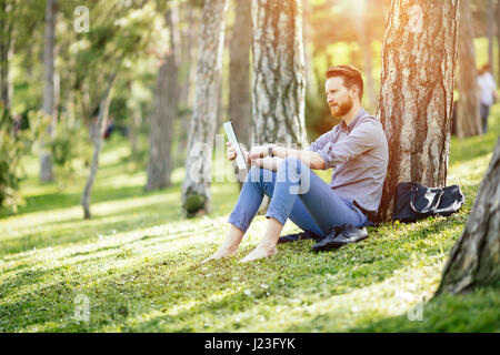 Gut aussehend Geschäftsmann mit TabletPC im park Stockfoto