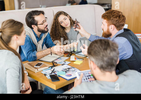 Junge Designer zeigen seine Kollegen etwas Merkwürdiges in smartphone Stockfoto