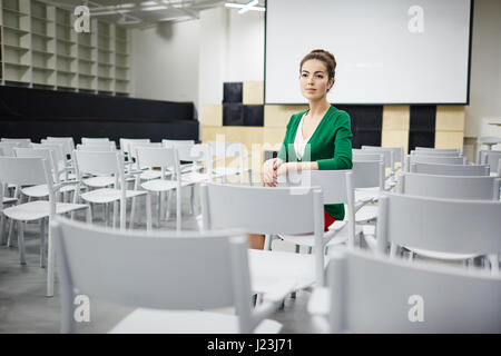 Junge Lehrer oder Schüler sitzen in Reihe auf einem der Stühle im Hörsaal Stockfoto