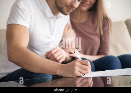 Nahaufnahme des jungen Brautpaares Unterzeichnung Papiere, Eigentum zu erwerben, Stockfoto