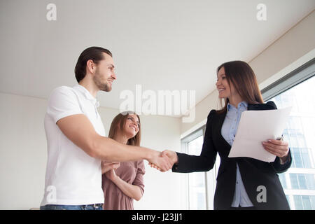 Menschen und Immobilien. Junges Paar und weibliche Broker handshaki Stockfoto