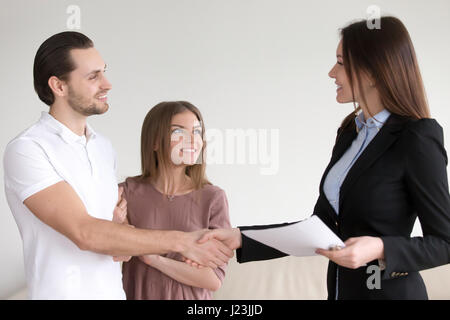 Ehepaar Händeschütteln mit Immobilienmakler im neuen Zuhause Stockfoto