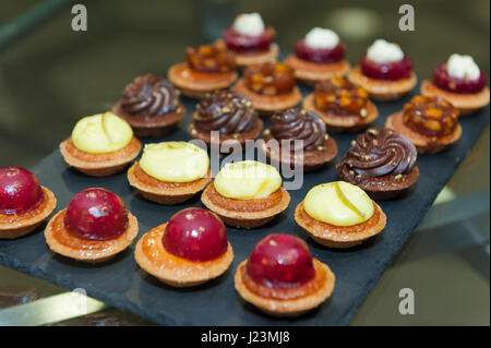 schwarze quadratische Platte mit kleinen Miniatur Kuchen auf Stockfoto