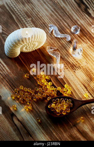 Kerze in der Form von Muscheln, Fischöl und ein Seepferdchen auf Holzuntergrund Stockfoto