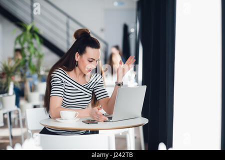 Schöne Frau reden über das Internet über ihr Unternehmen und arbeiten Probleme. Frauen sitzen in einem Café bei einer Tasse Kaffee und reden. Stockfoto