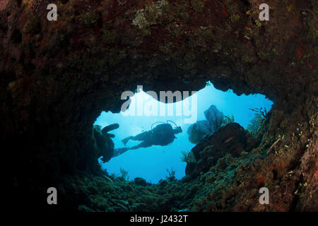 Taucher schwimmt in Richtung Öffnung im Riff. Stockfoto