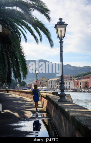 Street View von Bosa, Sardinien, Italien am Tag. Schöne junge Frau zu Fuß durch den Fluss. Ansicht von hinten an einem sonnigen Tag. Stockfoto