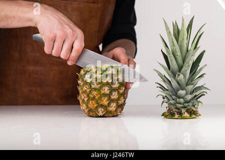 Closeup auf Mannes Hände schneiden Ananas Stockfoto