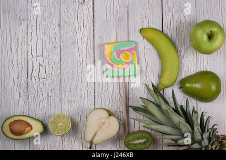 Hälften des reifen tropischen Früchten platziert auf einem Holzbrett mit bunten Süßigkeiten Stockfoto