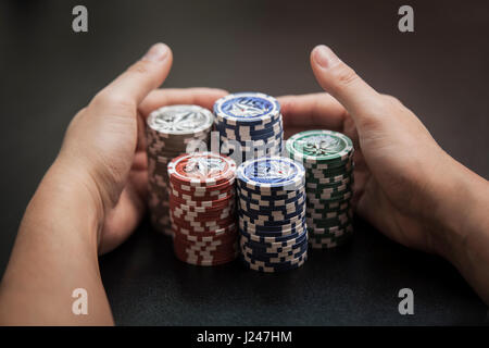 Mannes Hände ziehen sich einen grossen Haufen Pokerchips Stockfoto