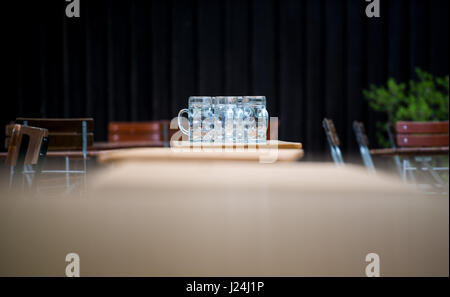 München, Deutschland. 25. April 2017. Leere Bierkrüge können auf einem nassen Tisch in einem Bier-Graden in München, Deutschland, 25. April 2017 gesehen werden. Foto: Alexander Heinl/Dpa/Alamy Live News Stockfoto