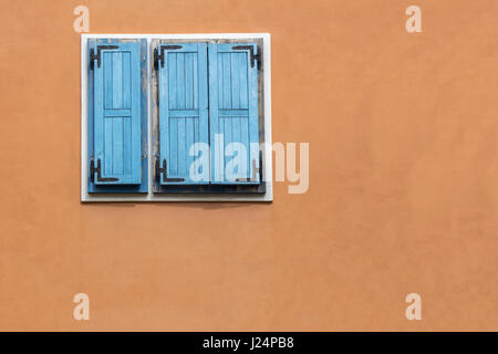 Blauen hölzernen Fensterläden auf der orangefarbenen Fassade Stockfoto