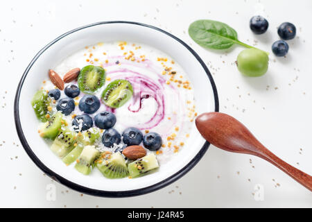 Vegan-Joghurt mit frischen Beeren, Früchten und Superfoods in Schüssel auf weißen Tisch Stockfoto