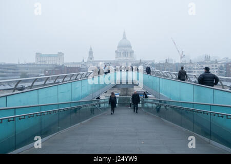 Pendler, die zu Fuß über die Millennium Bridge zu arbeiten mit Blick auf die St Paul's Kathedrale, eingehüllt in Nebel Stockfoto