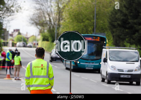 Manuell gesteuertes „Stop Go“-Schild für temporäre Straßenarbeiten, das zur Verkehrskontrolle auf einer stark befahrenen Stadtstraße in Chirk Wales verwendet wird Stockfoto