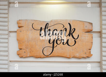 Leere Holzplatte auf Wand und Text Thank You. Kalligraphie-Schriftzug Hand zeichnen Stockfoto