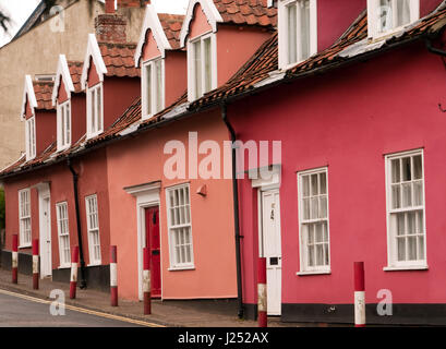 Reihe von Reihenhaus Hütten gemalt verschiedene Schattierungen von Rosa, mit roten und weißen Poller vor, Bungay, Suffolk, England, UK Stockfoto