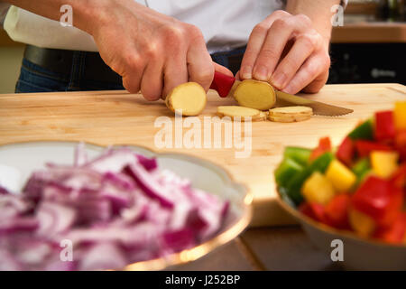 Mannes Hände schneiden frische Tomaten in der Küche eine Mahlzeit zuzubereiten, für das Mittagessen. Topdown-Ansicht. Stockfoto