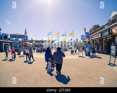 Familie Touristen am Pier 39, Fishermans Wharf, San Francisco, Kalifornien, USA, zwei Frauen und Kinder, blauen und gelben Fahnen, Hintergrundbeleuchtung, Vintage-Ton Stockfoto