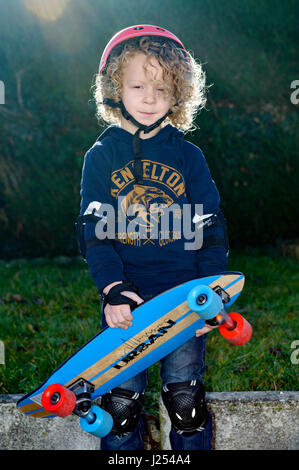 kleinen blonden und lockigen jungen mit dem skateboard Stockfoto