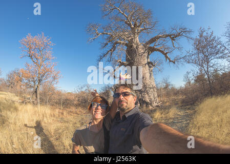 Paar nehmen Selfie in der Nähe von Baobab-Werk in der afrikanischen Savanne mit klaren blauen Himmel. Fisheye Blick von unten getönt Bild. Wildnis Safari und advent Stockfoto