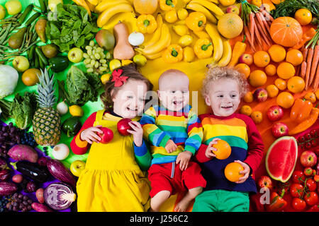 Junge, Mädchen und Babys mit Vielzahl von Obst und Gemüse. Bunte Regenbogen von rohem Obst und Gemüse. Kind, gesunden Snack zu essen. Vegetarische nutritio Stockfoto