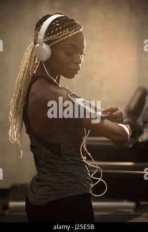 Fit Woman mit Smartphone in Armbinde in Turnhalle Stockfoto