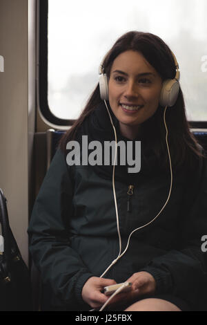 Frau Musik hören auf Smartphone beim Sitzen im Zug Stockfoto