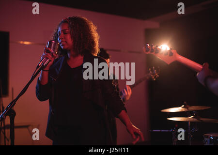 Frau singt auf Retro-Mikrofon im Tonstudio Stockfoto