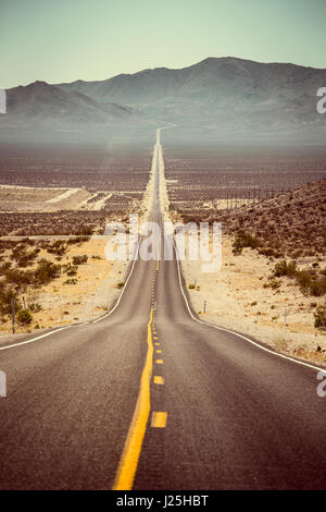 Klassische Panoramablick auf eine endlose geraden Straße laufen durch die karge Landschaft des amerikanischen Südwestens im Sommer Stockfoto