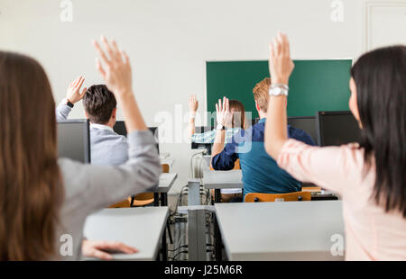 Junge Studenten, die Hände in einem Klassenzimmer zeigen, dass sie bereit sind Stockfoto