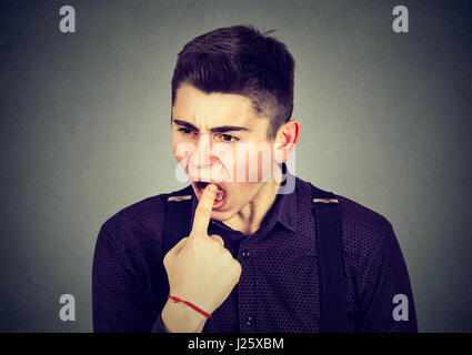 angewidert Mann mit Finger im Mund unzufrieden will kotzen auf graue Wand Hintergrund isoliert. Menschliche Emotionen Körpersprache Stockfoto