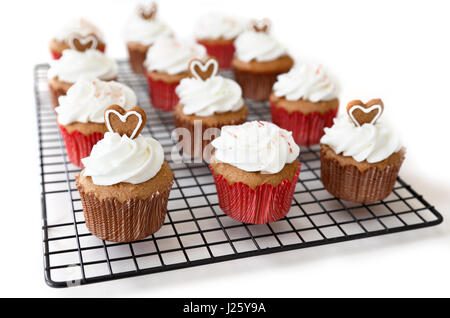 Gewürz-Muffins verziert mit Lebkuchenherzen und Candy Cane Crush auf weißem Hintergrund Stockfoto