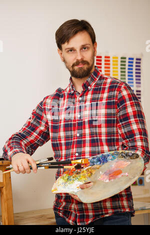 Mann-Künstler hält in seinen Händen, einen Pinsel und eine Holzpalette mit Ölfarben. Porträt. Stockfoto