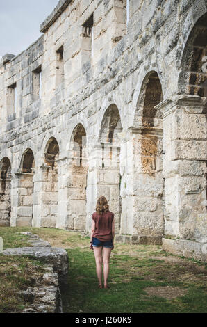 Junge Frau, die zu Fuß durch die antike römische Amphitheater, Arena in Pula, Kroatien Stockfoto