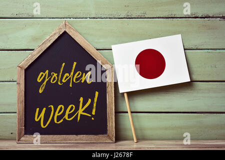 eine Haus-förmigen Tafel mit dem Text Goldene Woche geschrieben und eine Fahne von Japan, gegen einem blassen Grün rustikalen hölzernen Hintergrund Stockfoto