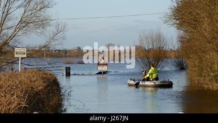 Paar paddeln ein Beiboot auf einer stark überflutet und geschlossene Straße auf Curry-Moor, North Curry, Somerset Levels, UK, Februar 2014. Stockfoto