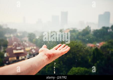 Regnerischen Tag in der Stadt. Regentropfen fallen auf der Hand. Kuala Lumpur, Malaysia Stockfoto