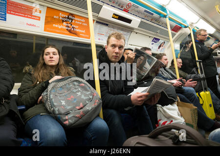 Fahrgäste lesen Zeitungen in einer Londoner U-Bahn u-Bahn Zug, London, England, UK Stockfoto